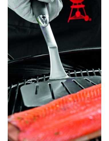 Spatola Weber da pesce in inox mentre gira del salmone su placca di cedro